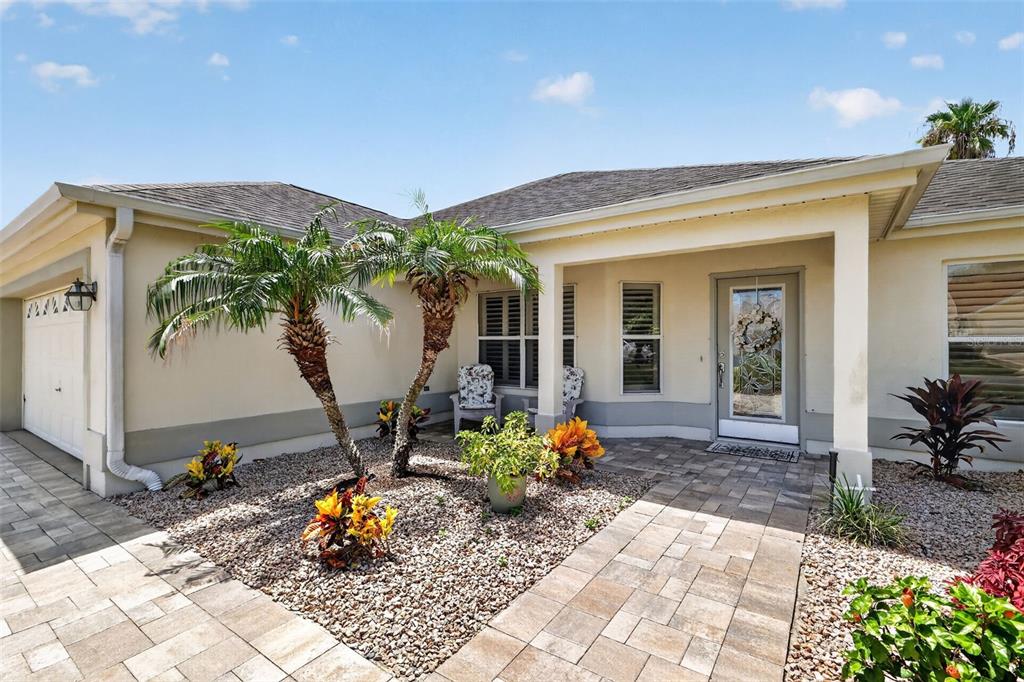 The exterior of a house features a paved walkway, palm trees, and a front entrance — 1808 SANTANA WAY, THE VILLAGES, FL