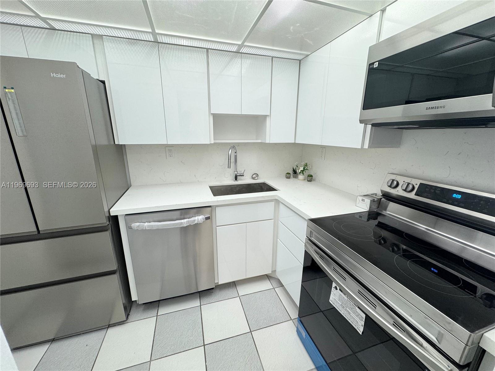 A modern kitchen features white cabinets, stainless steel appliances, and a white countertop — 2899 Collins Ave # 740, Miami Beach FL 33140, MIAMI BEACH, FL