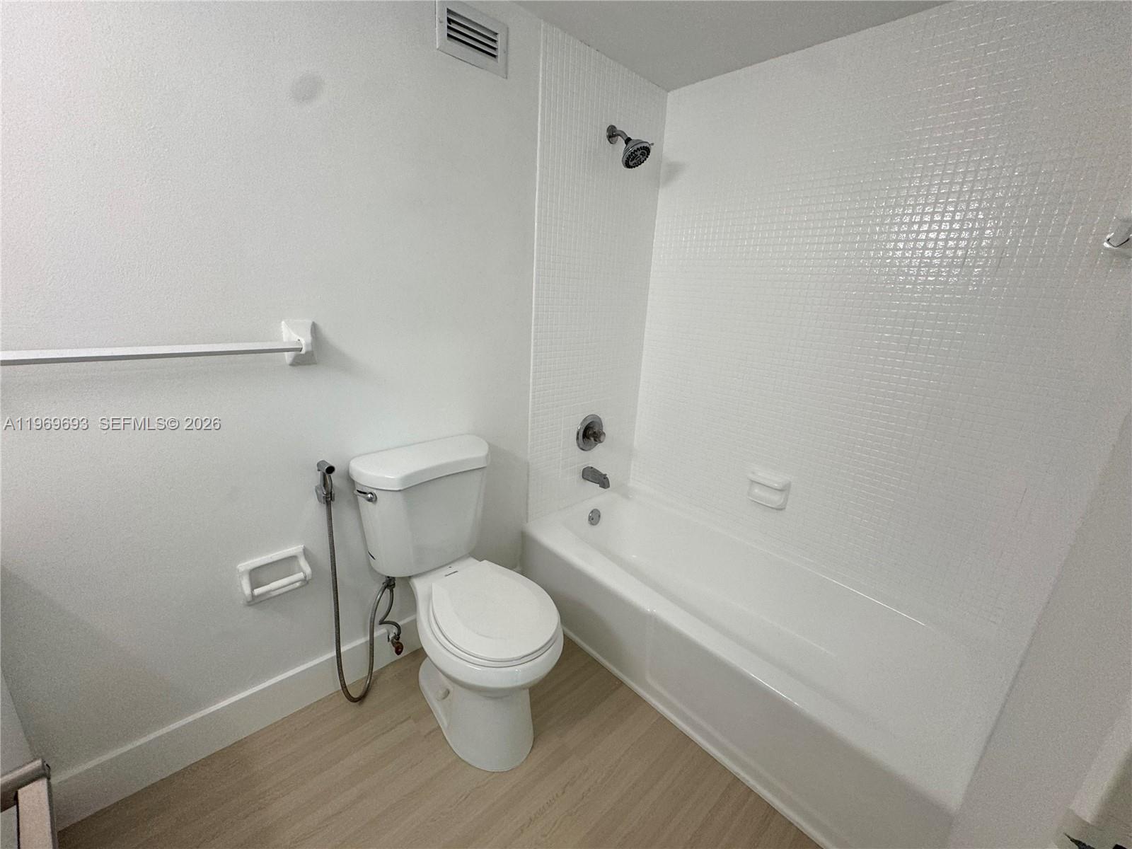 A bathroom features a white toilet, a bathtub with a showerhead, and light-colored flooring — 2899 Collins Ave # 740, Miami Beach FL 33140, MIAMI BEACH, FL
