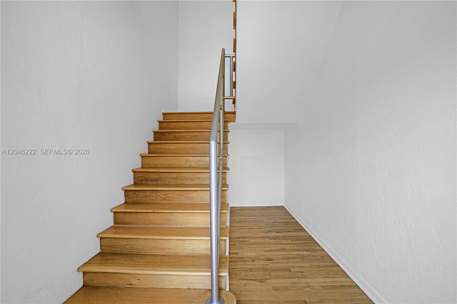 A wooden staircase with a metal railing leads upward against plain white walls — 1600 Michigan Ave # 6, Miami Beach FL 33139, MIAMI BEACH, FL