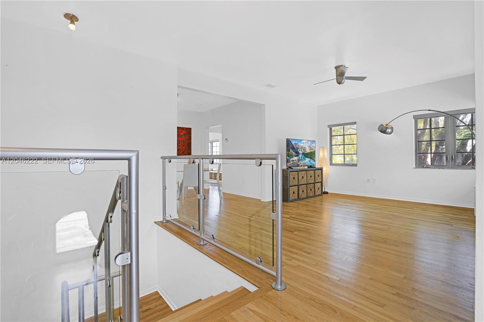 A bright living area features hardwood floors, a glass railing, and a ceiling fan — 1600 Michigan Ave # 6, Miami Beach FL 33139, MIAMI BEACH, FL
