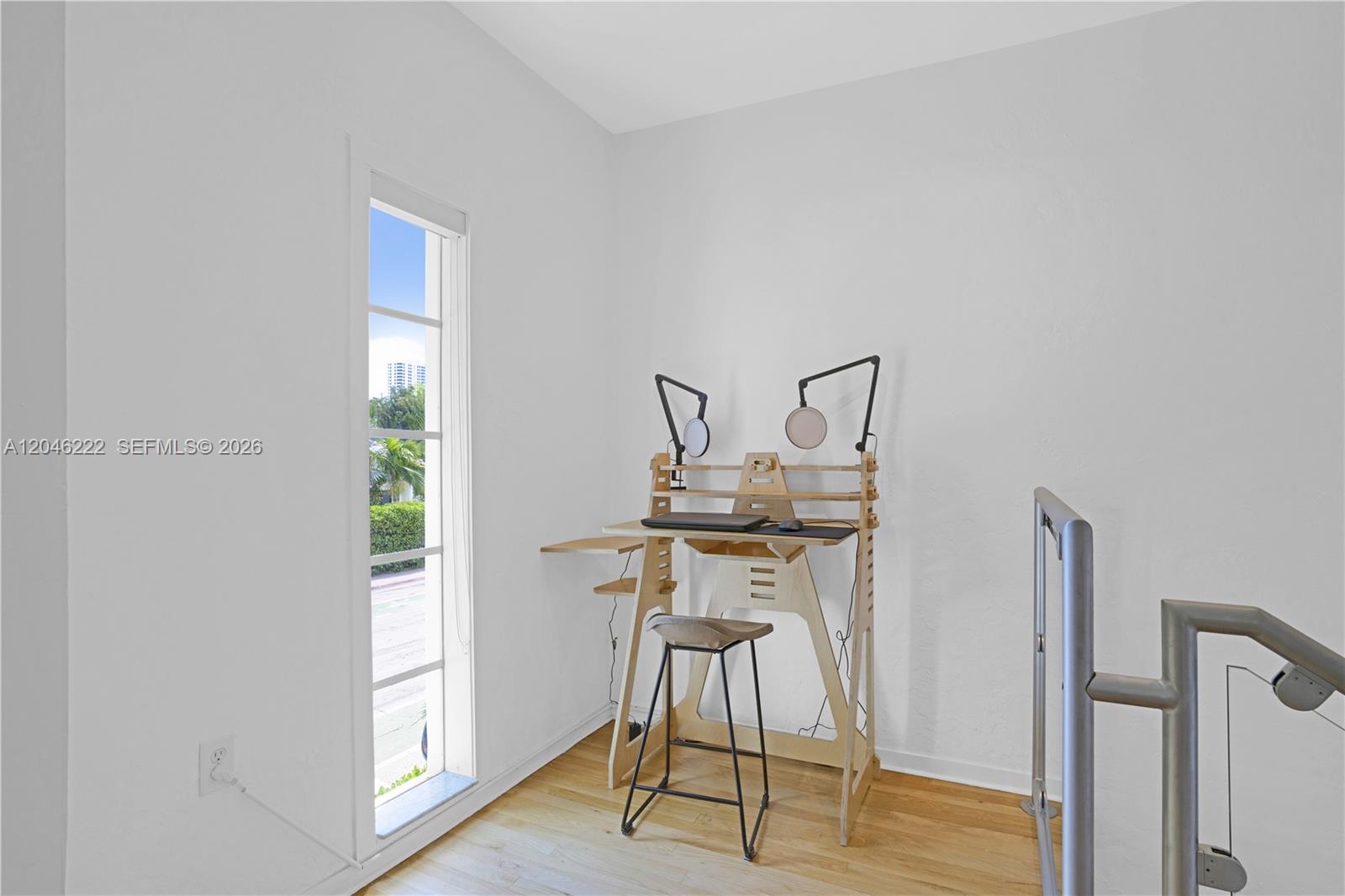A small home office area features a wooden standing desk and stool near a window — 1600 Michigan Ave # 6, Miami Beach FL 33139, MIAMI BEACH, FL