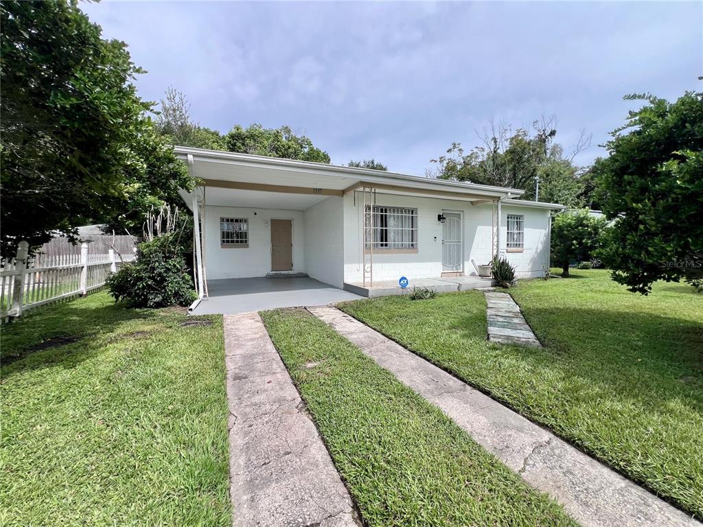 A single-story white house with a carport, a concrete driveway, and a front lawn — 1517 RILEY AVENUE, ORLANDO, FL