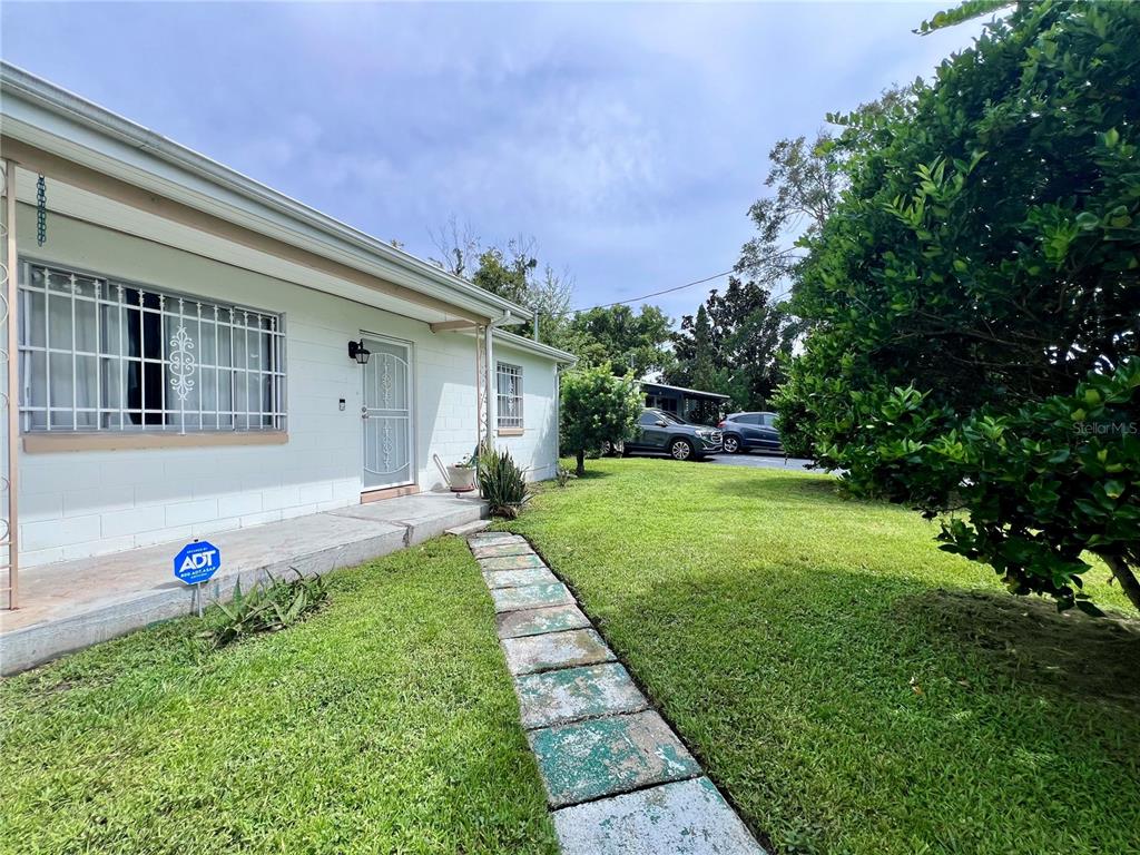 A white house with a concrete walkway and a green lawn under a cloudy sky — 1517 RILEY AVENUE, ORLANDO, FL
