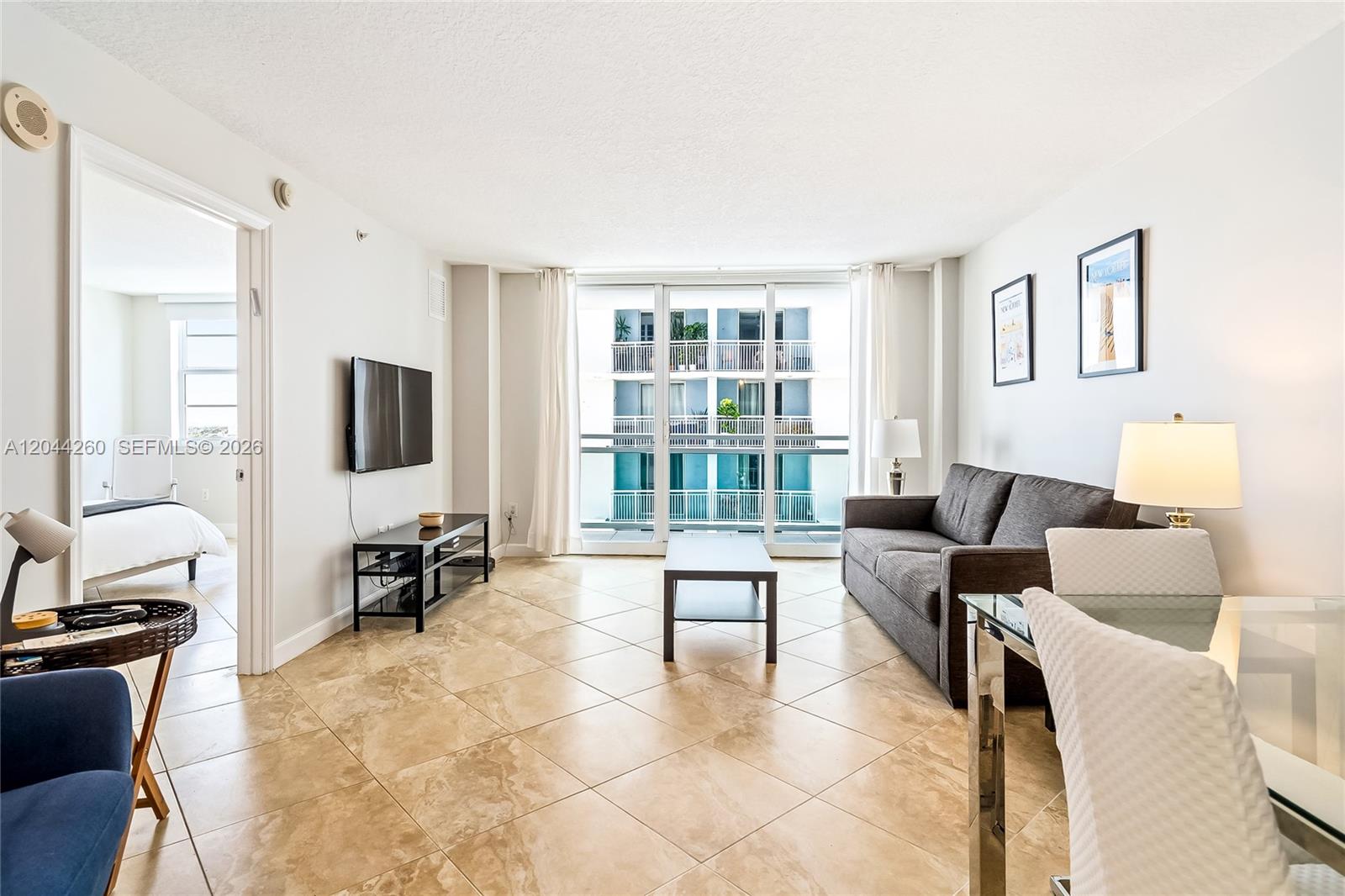 A living room features tile flooring, a grey sofa, a coffee table, and balcony access — 6917 Collins Ave # 1012, Miami Beach FL 33141, MIAMI BEACH, FL