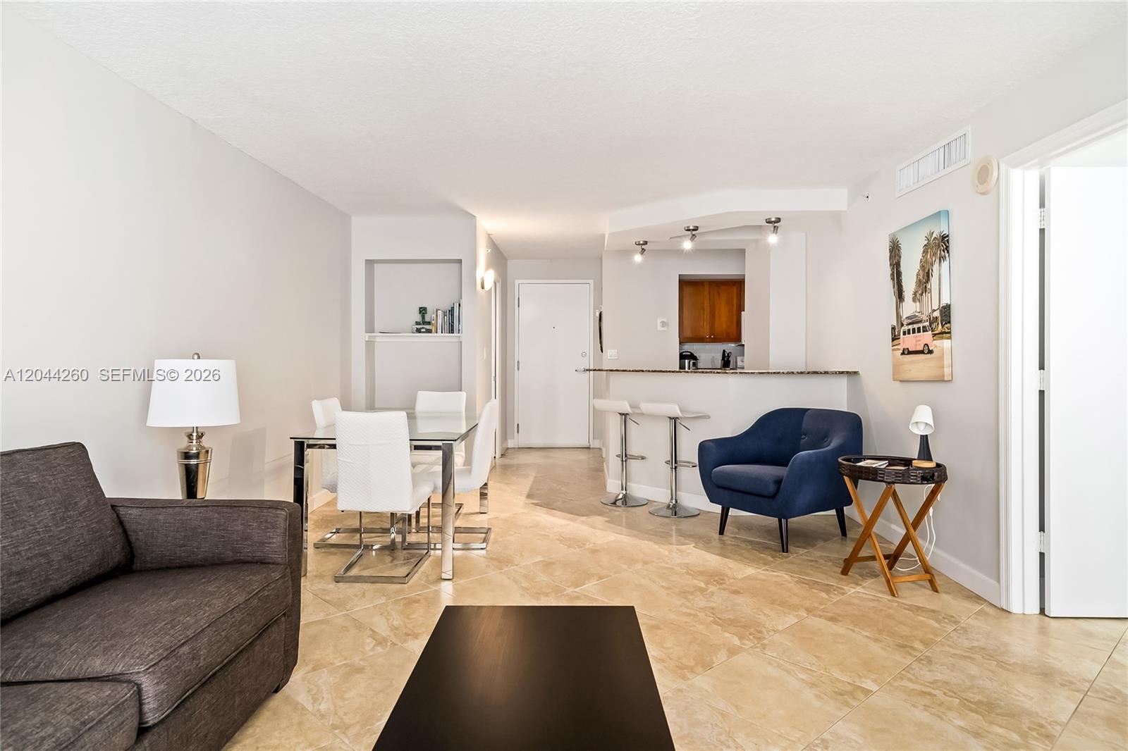A living and dining area features tile floors, a breakfast bar, and a blue armchair — 6917 Collins Ave # 1012, Miami Beach FL 33141, MIAMI BEACH, FL