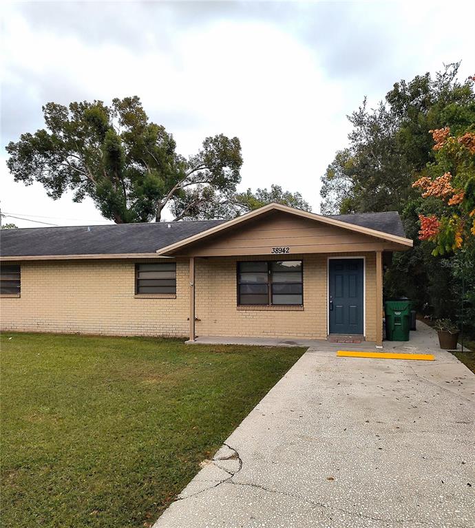 A single-story brick house with a concrete driveway and a covered front porch — 38942 9TH AVENUE, ZEPHYRHILLS, FL