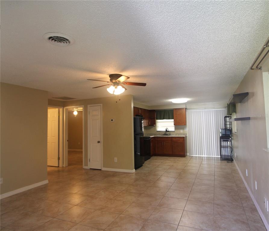 An open-concept living area features tile flooring, a ceiling fan, and an adjacent kitchen — 38942 9TH AVENUE, ZEPHYRHILLS, FL