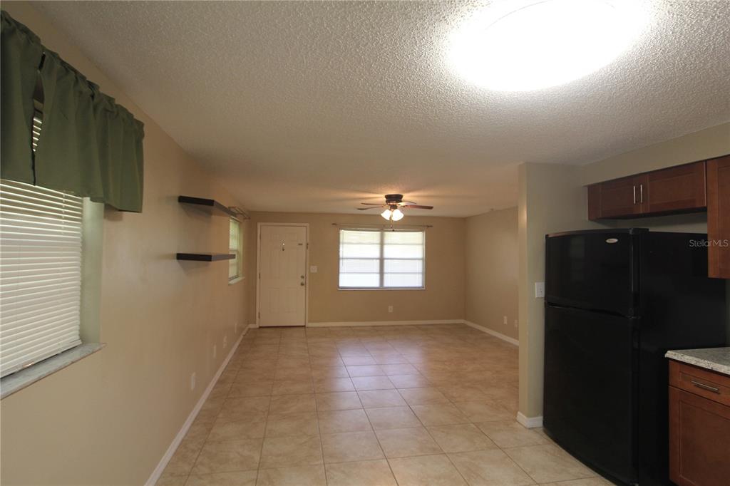 A kitchen and living area feature tile floors, a ceiling fan, and a black refrigerator — 38942 9TH AVENUE, ZEPHYRHILLS, FL