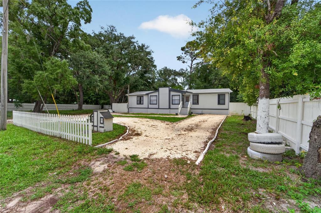 A single-story manufactured home with light siding, dark trim, and a gravel driveway — 9690 JEROME DRIVE, NEW PORT RICHEY, FL