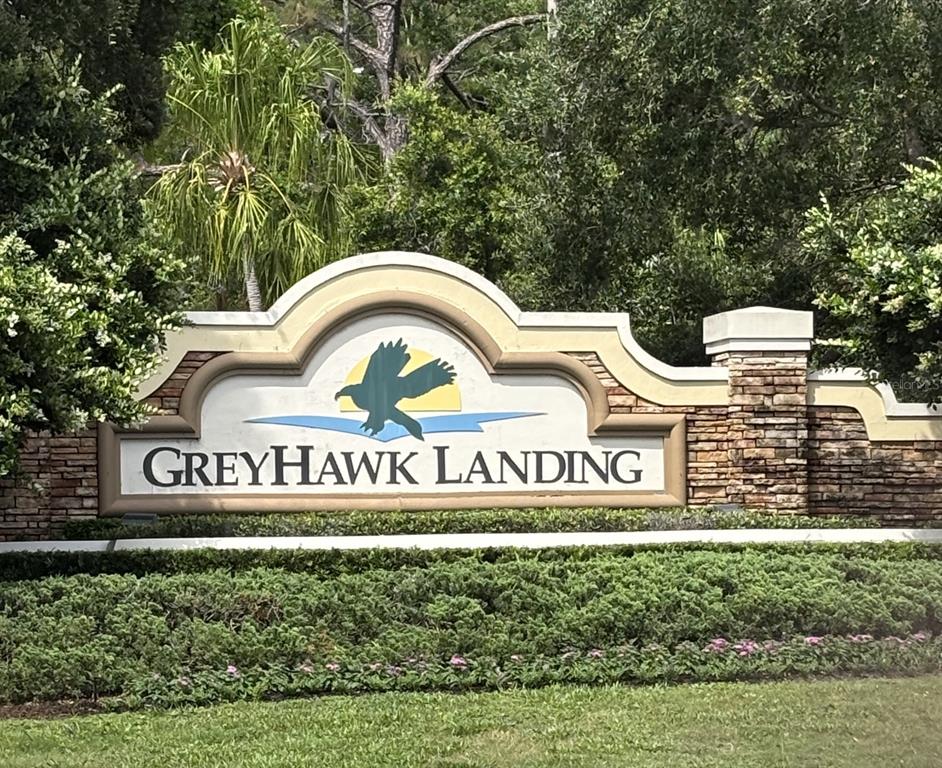 A stone and stucco monument sign for Greyhawk Landing stands in front of lush landscaping — 267 PETREL TRAIL, BRADENTON, FL