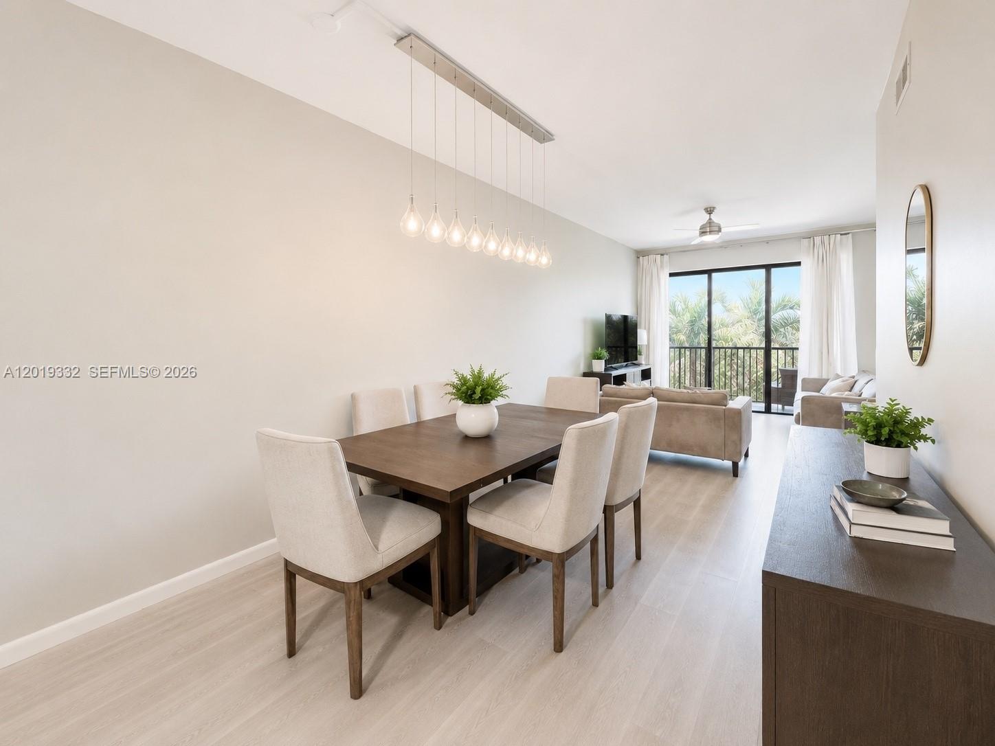 A dining area with a wooden table and chairs sits adjacent to a living room — 8816 Collins Ave # 206, Surfside FL 33154, SURFSIDE, FL