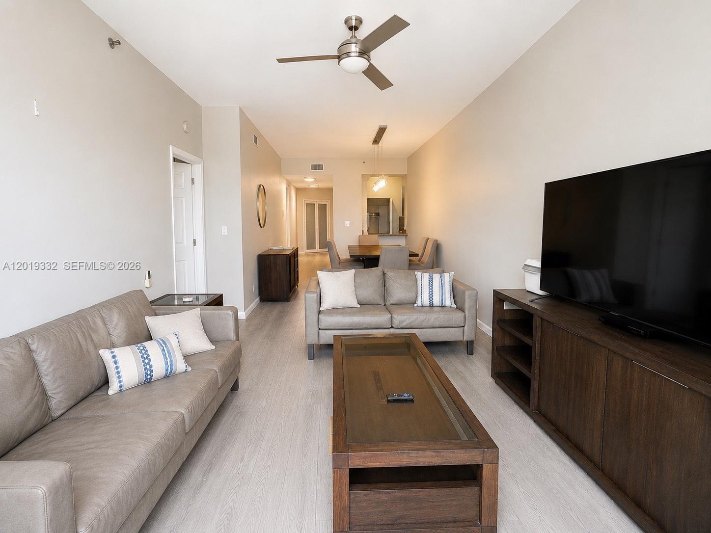 A living room features two gray leather sofas, a wooden coffee table, and a television — 8816 Collins Ave # 206, Surfside FL 33154, SURFSIDE, FL