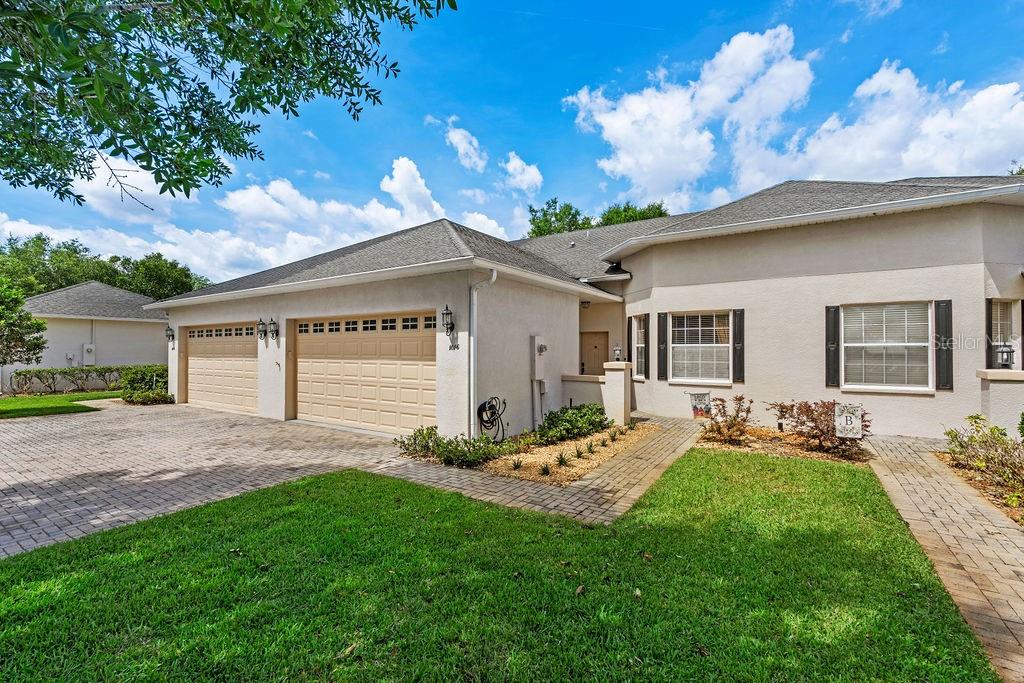 A beige stucco house with a three-car garage and a paved walkway — 1016 GREEN GATE BOULEVARD, GROVELAND, FL