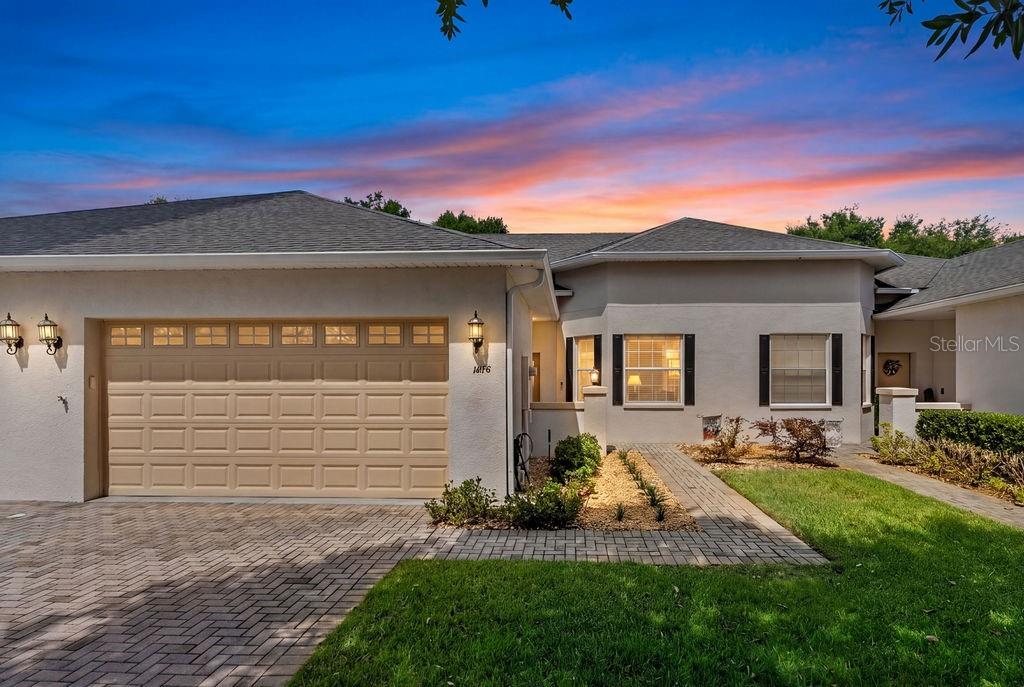 A single-story house with a beige garage door, light stucco walls, and a paver walkway — 1016 GREEN GATE BOULEVARD, GROVELAND, FL