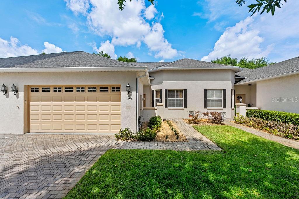 A single-story house exterior features a tan garage, a paved driveway, and a front walkway — 1016 GREEN GATE BOULEVARD, GROVELAND, FL