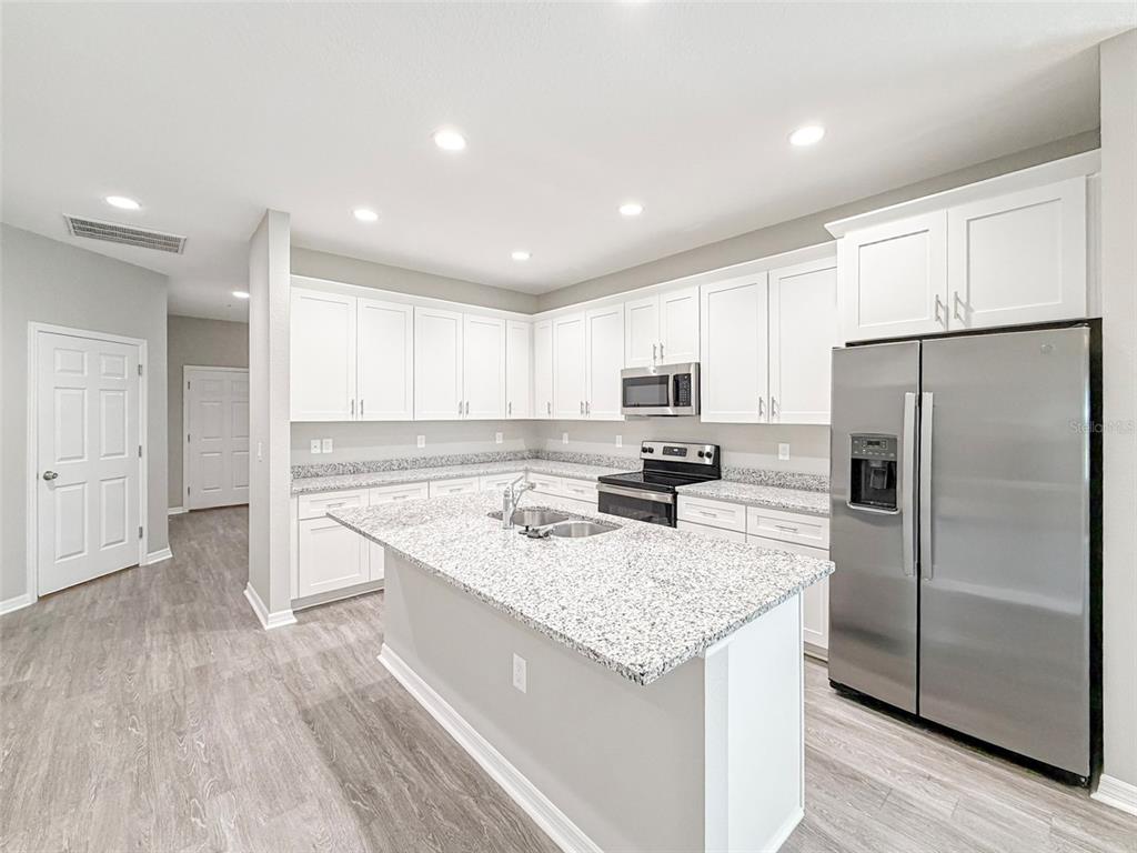 A kitchen features white cabinets, granite countertops, a center island, and stainless steel appliances — 3376 CUP DRIVE, LAKELAND, FL