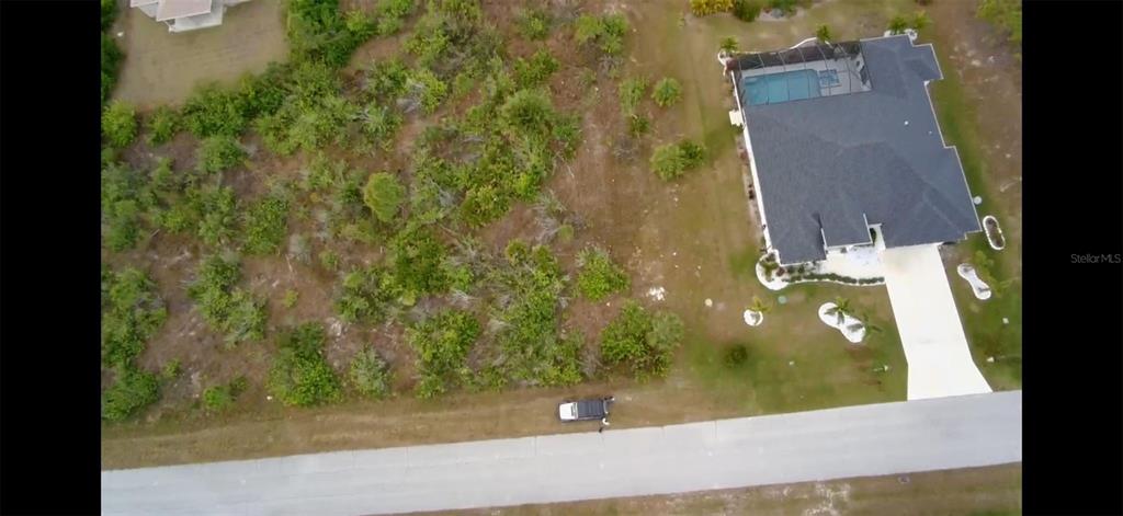 An aerial view shows a vacant, wooded lot next to a house with a pool — 9517 SUNDANCE STREET, PORT CHARLOTTE, FL