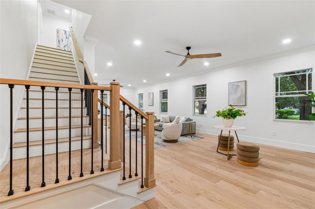 A bright living room features light wood floors, a staircase with black railings, and recessed lighting — 2722 N MYRTLE AVENUE, TAMPA, FL