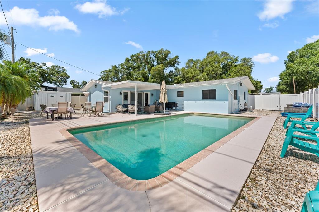 A light blue house with a swimming pool and patio area in the backyard — 2833 56TH LANE N, ST PETERSBURG, FL
