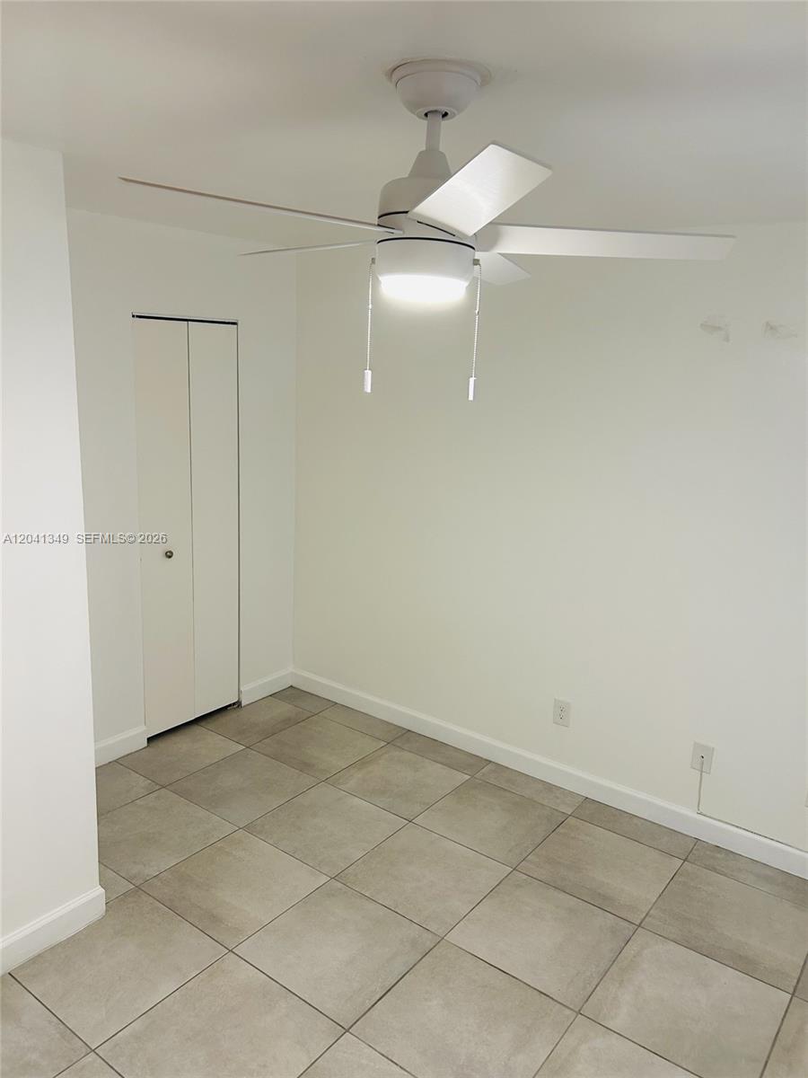 A room with white walls, tiled flooring, a ceiling fan, and a closed closet door — 15325 SW 106th Ter # 614, Miami FL 33196, MIAMI, FL