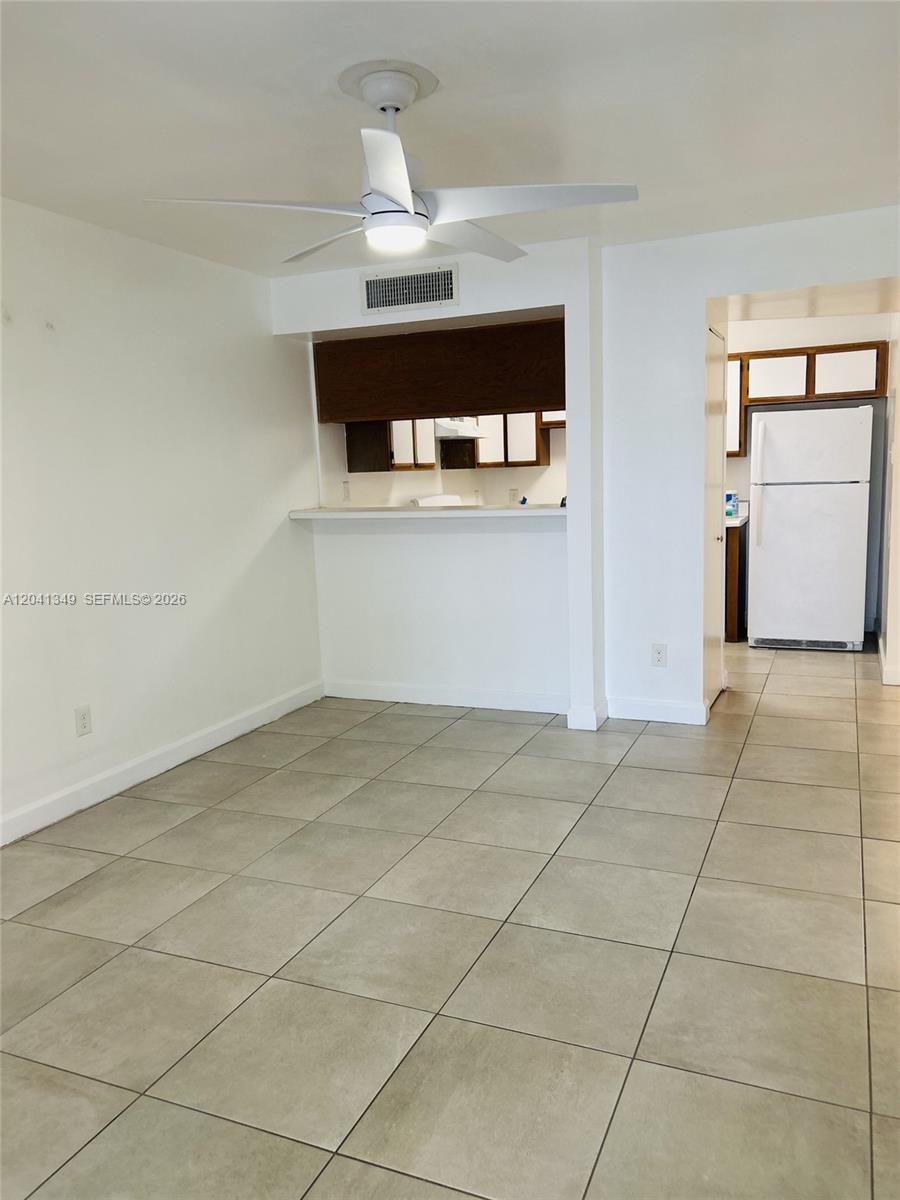 This room features light-colored tile flooring, a ceiling fan, and a kitchen pass-through window — 15325 SW 106th Ter # 614, Miami FL 33196, MIAMI, FL