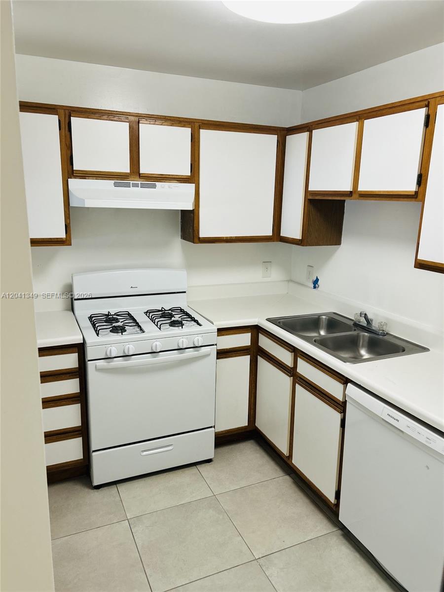 A kitchen features white appliances, white cabinets with wood trim, and light-colored tile flooring — 15325 SW 106th Ter # 614, Miami FL 33196, MIAMI, FL