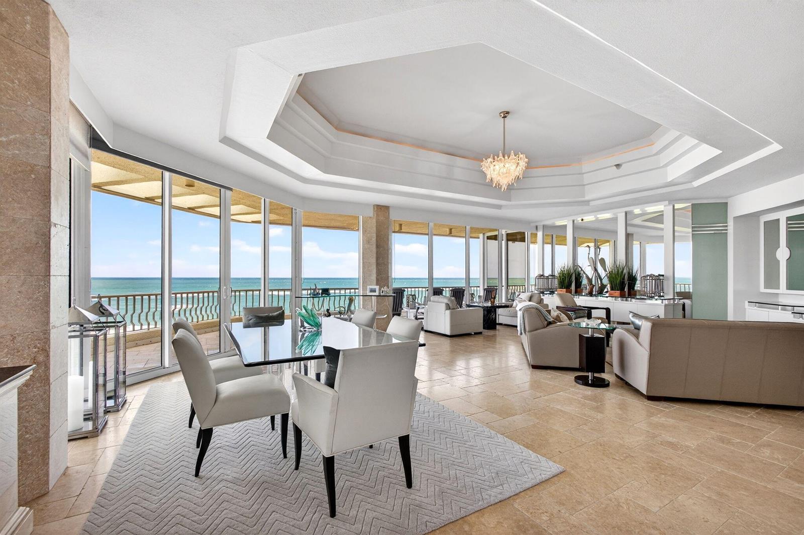 A spacious living and dining area features tile floors, a tray ceiling, and floor-to-ceiling windows — 2920 SE Dune Drive # 420, Stuart FL 34996, STUART, FL