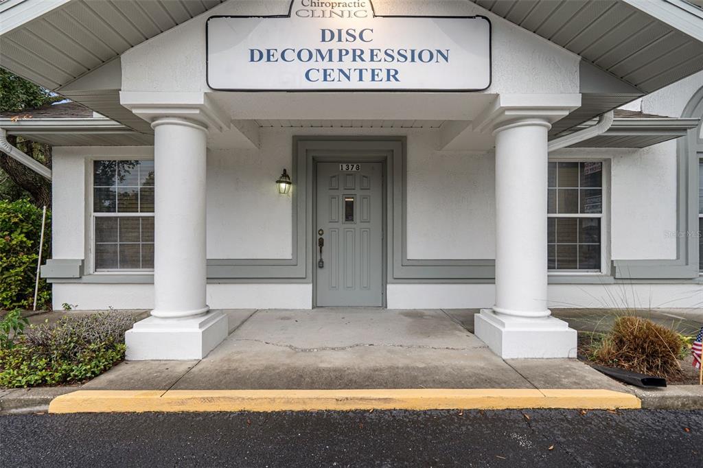 The exterior entrance of a chiropractic clinic features two white columns and a gray door — 1377 DELTONA BOULEVARD, SPRING HILL, FL