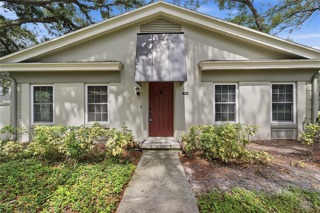 An open-concept room features light-colored tile flooring, beige walls, and a white entry door — 6214 DEWDROP WAY, TEMPLE TERRACE, FL