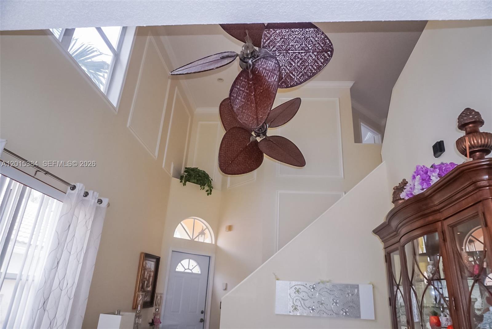A high-ceilinged entryway features a dual-fan fixture, a staircase, and a wooden display cabinet — 6864 Sugarloaf Key St, Lake Worth FL 33467, LAKE WORTH, FL