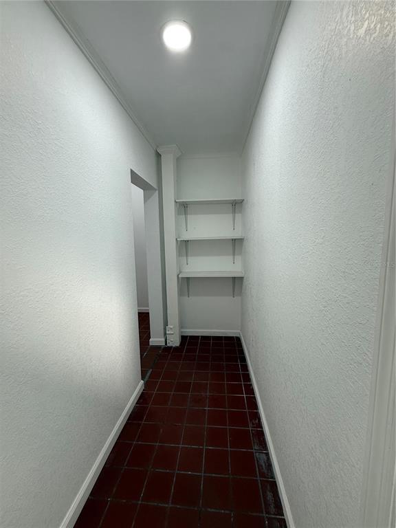 A narrow hallway features white walls, dark tiled flooring, and three built-in wall shelves — 501 ATHENS STREET UNIT A & B, TARPON SPRINGS, FL
