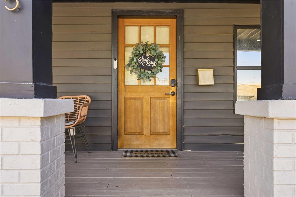 A wooden front door with a wreath sits on a porch with dark siding — 2925 24TH STREET N, ST PETERSBURG, FL