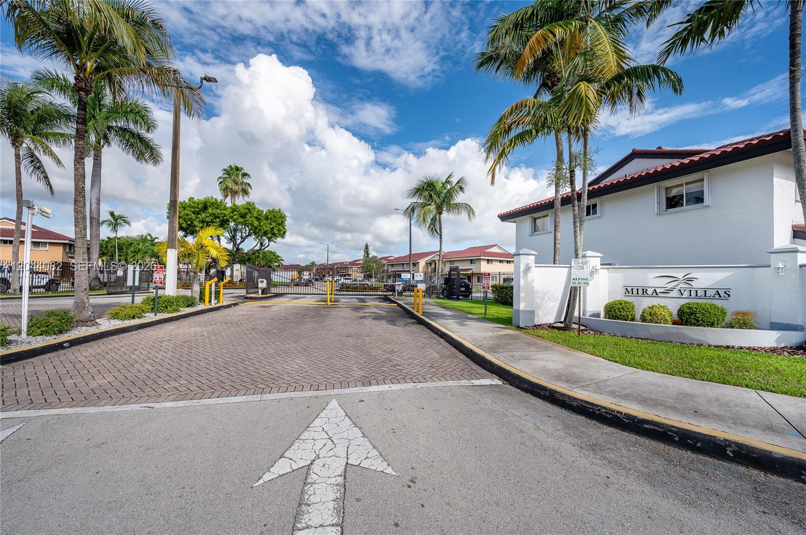 A gated entrance with a paved driveway leads to a residential complex named Mira Villas — 550 NW 82nd Ct # 383, Miami FL 33126, MIAMI, FL