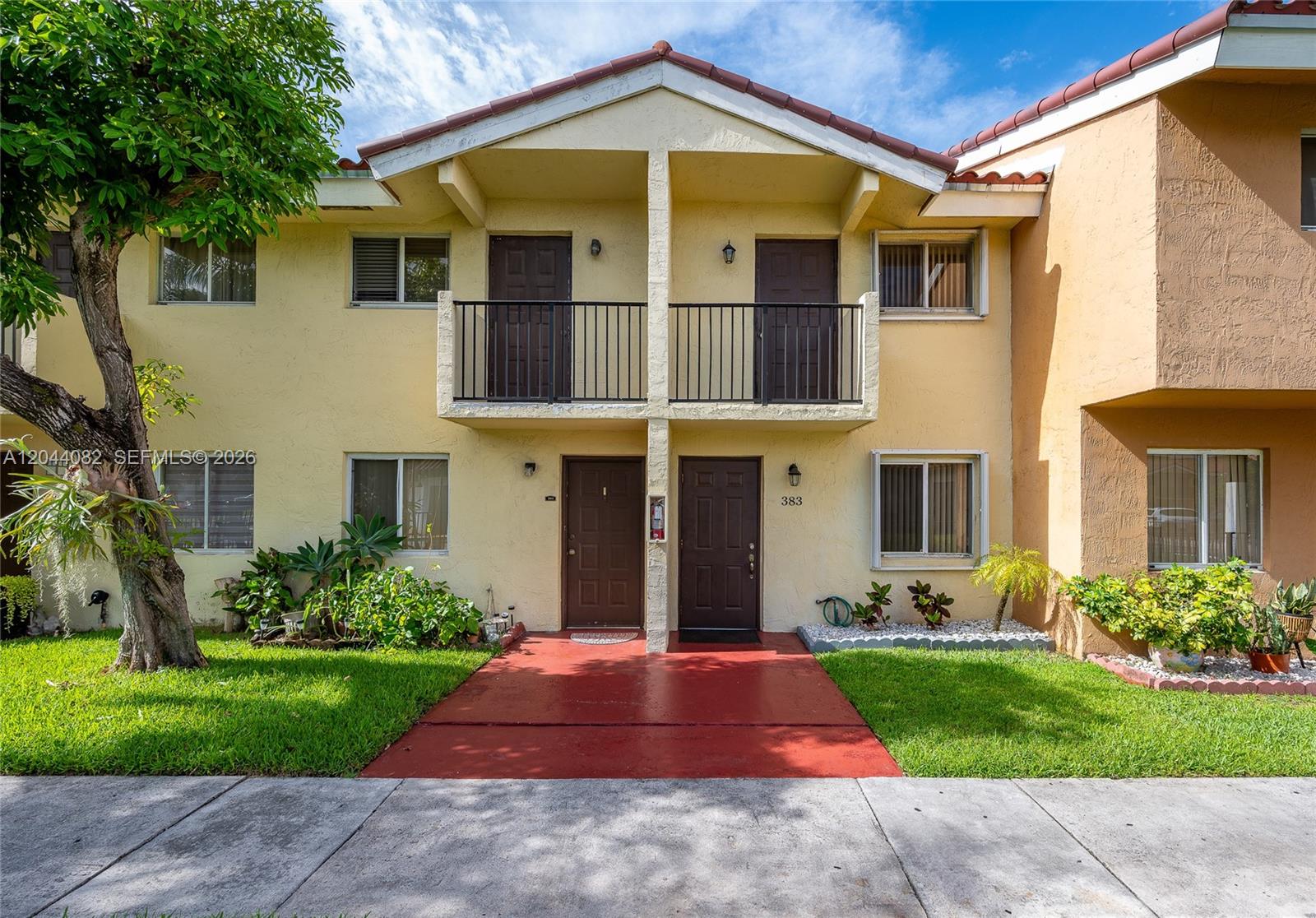 The exterior of a two-story residential building features yellow stucco walls and brown doors — 550 NW 82nd Ct # 383, Miami FL 33126, MIAMI, FL