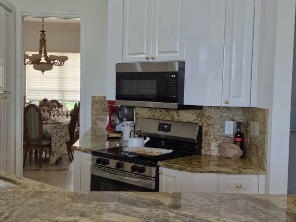 A kitchen features white cabinets, granite countertops, a stainless steel stove, and a microwave — 6671 E Liseron # 6671, Boynton Beach FL 33437, BOYNTON BEACH, FL