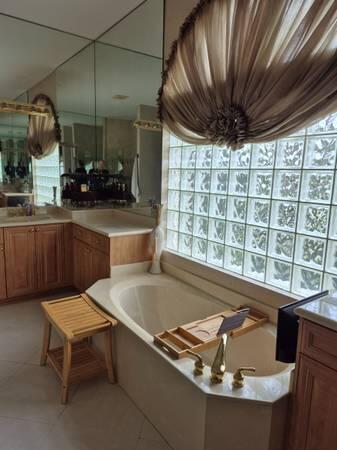 A bathroom features a soaking tub, glass block window, wooden cabinets, and a vanity mirror — 6671 E Liseron # 6671, Boynton Beach FL 33437, BOYNTON BEACH, FL