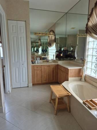A bathroom features light wood cabinets, a large mirror, a soaking tub, and tile flooring — 6671 E Liseron # 6671, Boynton Beach FL 33437, BOYNTON BEACH, FL