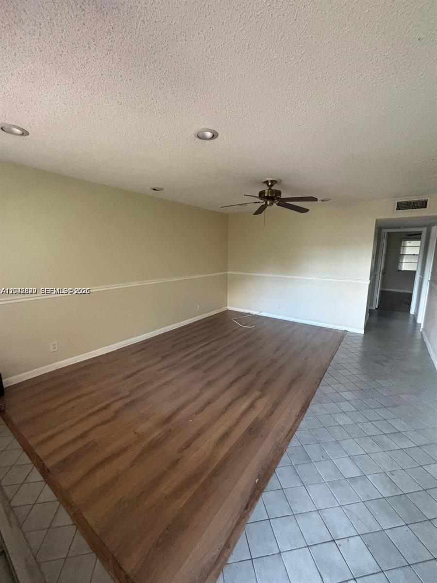 This room features wood-look flooring, a ceiling fan, and a transition to a tiled hallway — 280 Northampton, West Palm Beach FL 33417, WEST PALM BEACH, FL