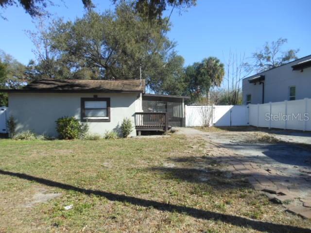 A small house with a wooden deck and a white vinyl fence in the backyard — 8421 N ORANGEVIEW AVENUE, TAMPA, FL