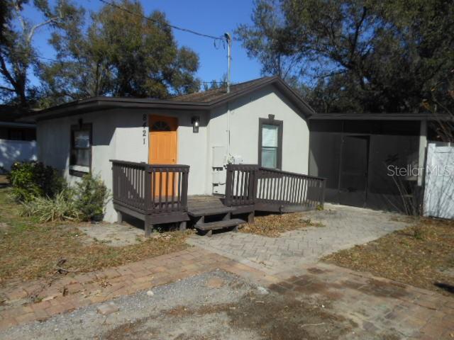 A small, single-story house with a brown wooden deck, orange door, and screened-in porch — 8421 N ORANGEVIEW AVENUE, TAMPA, FL
