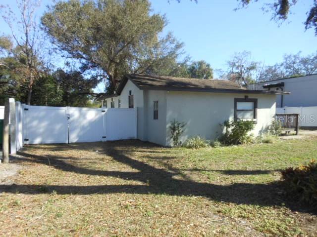 A single-story house with a white exterior and a white vinyl fence in the yard — 8421 N ORANGEVIEW AVENUE, TAMPA, FL