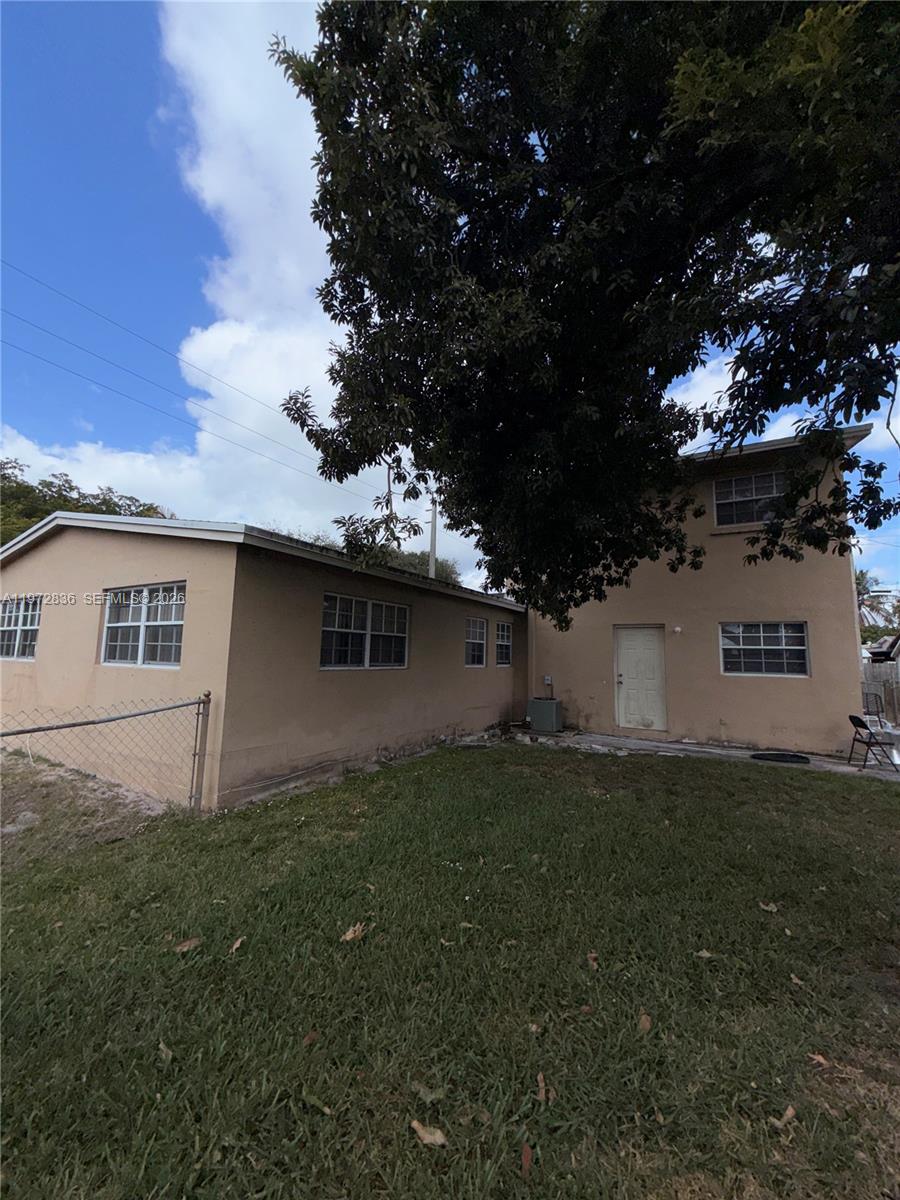 The exterior of a two-story tan house features a grassy yard and a large tree — 7191 Park St, Hollywood FL 33024, HOLLYWOOD, FL