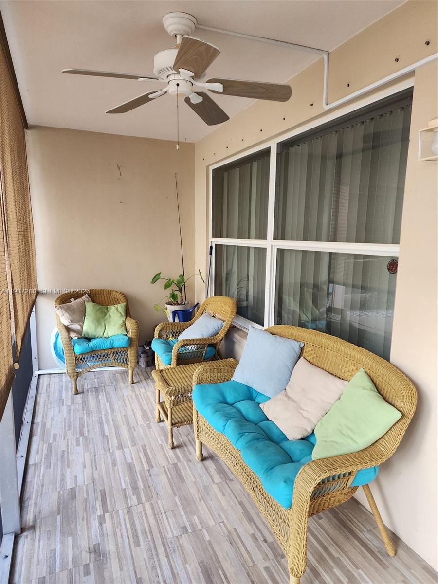 A covered balcony features wicker furniture, a ceiling fan, and light-colored wood-look flooring — 100 SE 6th Ave # 107, Pompano Beach FL 33060, POMPANO BEACH, FL