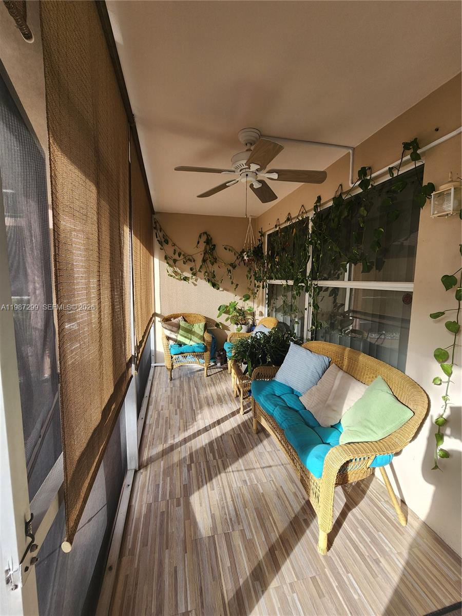 A screened-in porch features wicker furniture, a ceiling fan, and trailing plants on the walls — 100 SE 6th Ave # 107, Pompano Beach FL 33060, POMPANO BEACH, FL