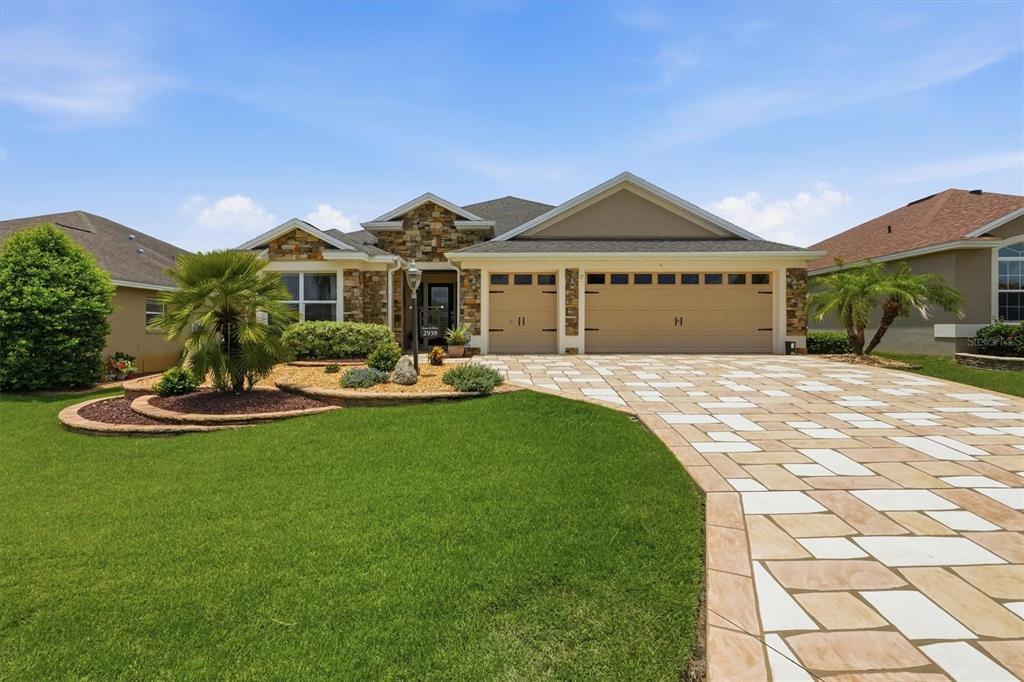 A single-story house with a stone facade, three-car garage, and a paved driveway — 2938 ADRIENNE WAY, THE VILLAGES, FL