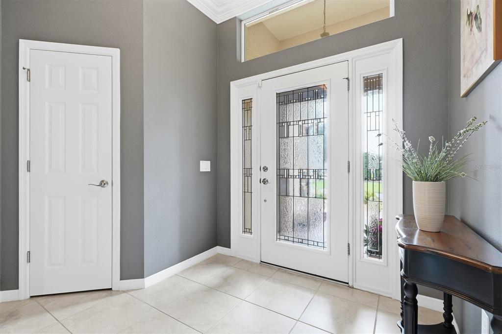 An entryway features a white front door with sidelights, gray walls, and light-colored tile flooring — 2938 ADRIENNE WAY, THE VILLAGES, FL
