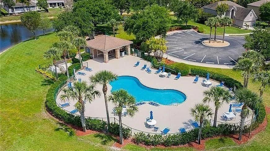 An aerial view shows a community swimming pool with a pavilion, lounge chairs, and parking — 24416 LAKEVIEW PLACE, PORT CHARLOTTE, FL
