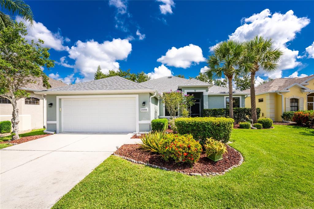 A single-story house with a two-car garage, a landscaped front yard, and palm trees — 24416 LAKEVIEW PLACE, PORT CHARLOTTE, FL