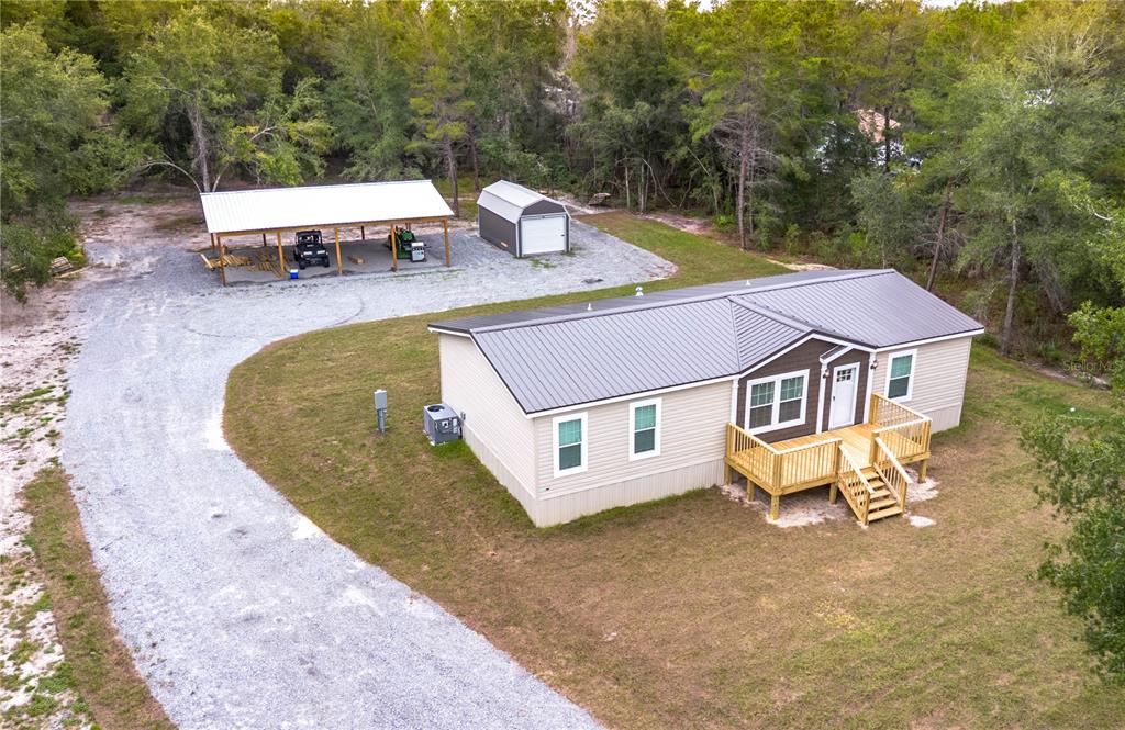 An aerial view shows a manufactured home with a deck, a carport, and a shed — 10865 NE 220TH STREET, FORT MC COY, FL